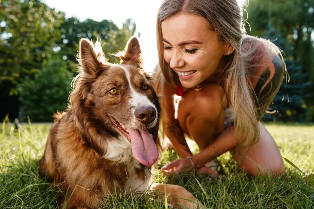 une fille donne une friandise à son chien couché sur l'herbe